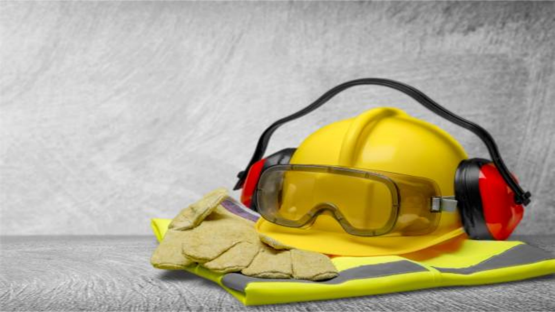 safety helmet with earphones and goggles on construction background